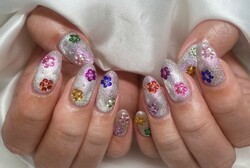 「ハンド ミドルコース」キラキラの上にカラフルなパーツでお花の形にしています|Nail Salon Linda