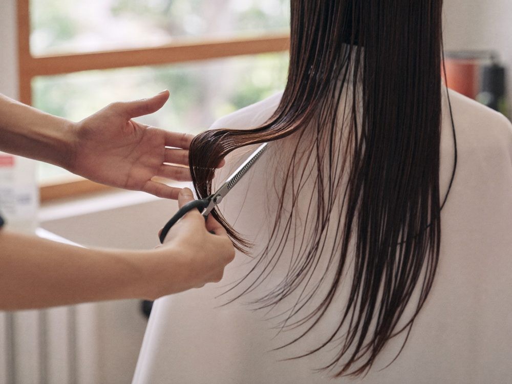 ヘアサロンでスタイリストが女性客の髪をカットしている様子